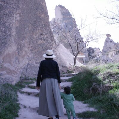 A woman and child walking on a rocky pathway in Cappadocia, Türkiye, highlighting its unique landscape.