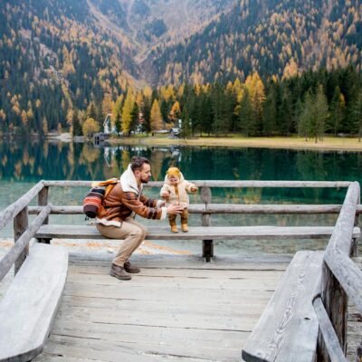Father and child sharing a joyful moment by a picturesque mountain lake during fall.