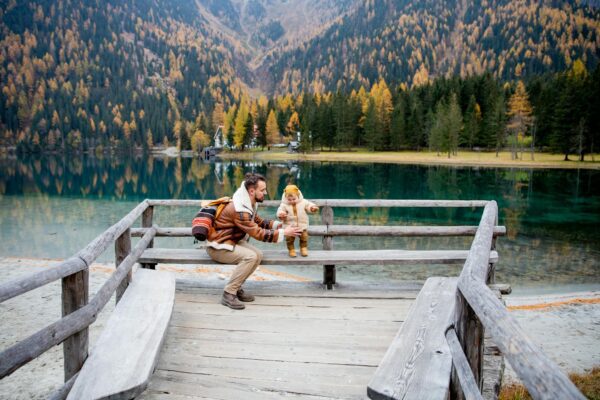 Father and child sharing a joyful moment by a picturesque mountain lake during fall.