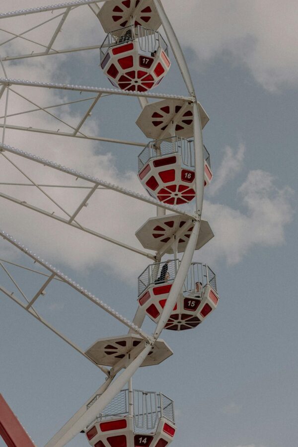 Red and white Ferris wheel cabins against a bright blue sky, capturing a lively fairground atmosphere.