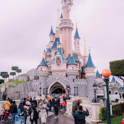 Visitors gather around the iconic Sleeping Beauty Castle at Disneyland Paris, a beloved tourist landmark.