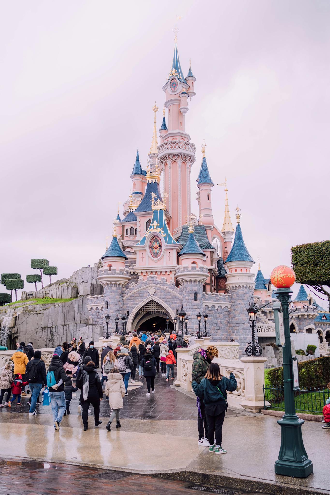 Visitors gather around the iconic Sleeping Beauty Castle at Disneyland Paris, a beloved tourist landmark.