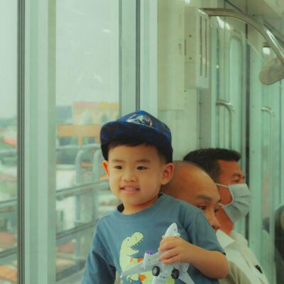 Young boy smiling on a train with family, capturing urban travel moments.