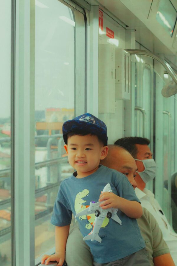Young boy smiling on a train with family, capturing urban travel moments.